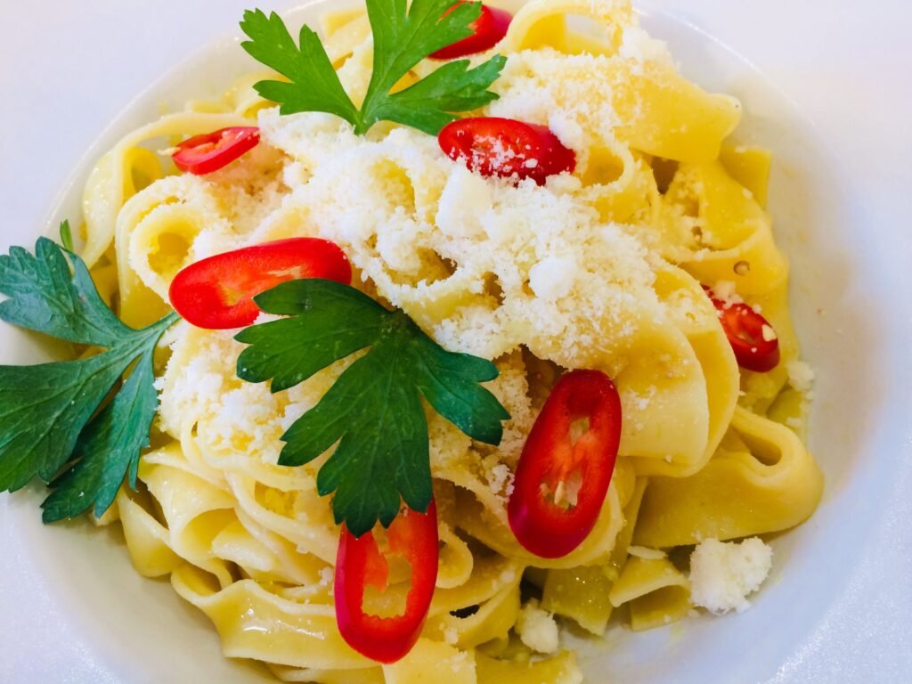 Come sbiancare i cuscini ingialliti facilmente Close-up of pasta dish with parmesan, red chilies, and fresh parsley on white plate.